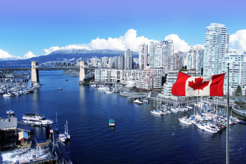 Canadian flag in front of view of False Creek and the Burrard street bridge in Vancouver, Canada.