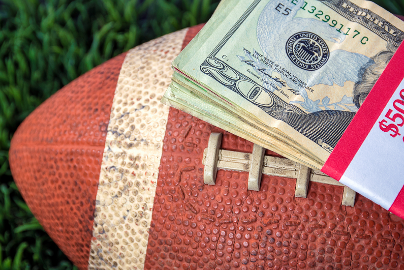 Stack of cash on top of a football.