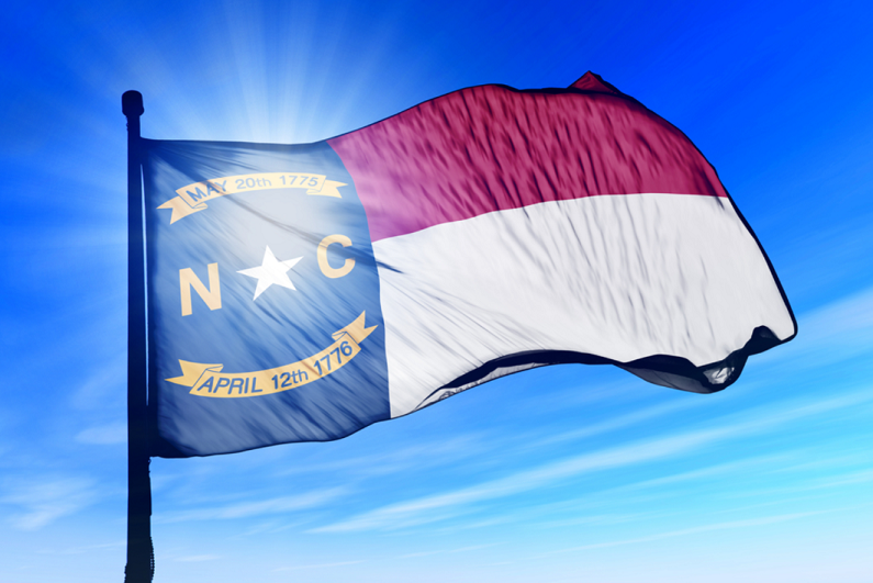 North Carolina flag waving against a blue sky.