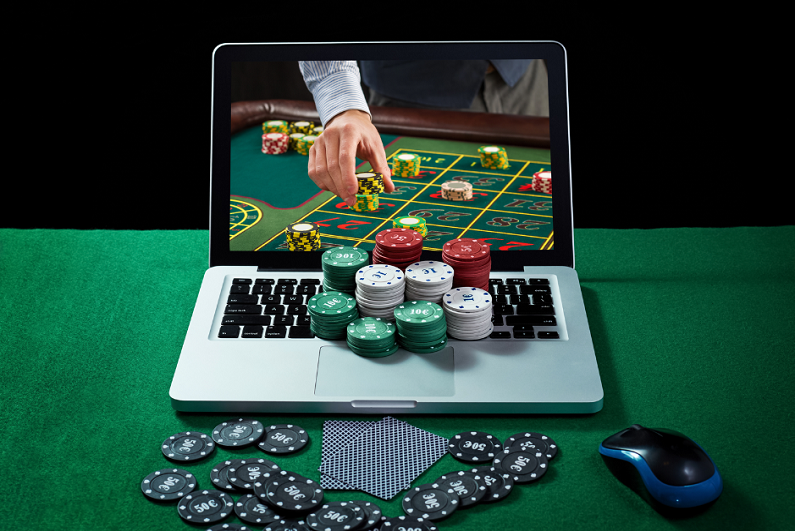 Green table with casino chips and cards on notebook.