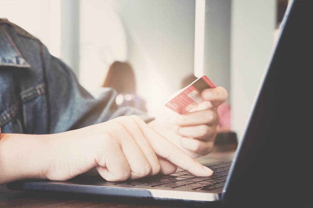 laptop user holding a credit card