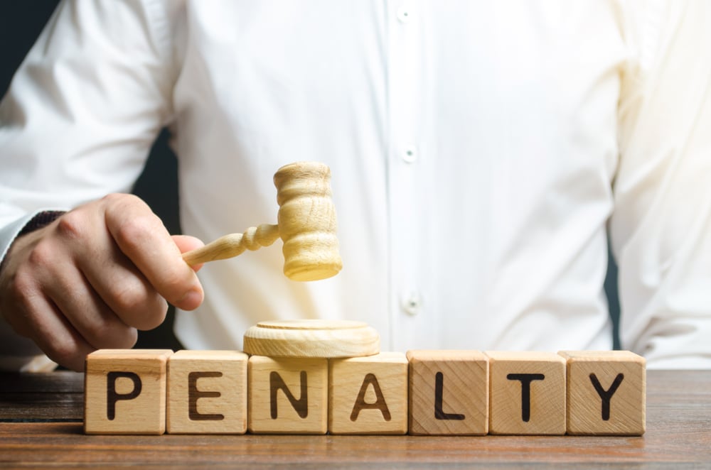 man hits gavel against blocks spelling out penalty