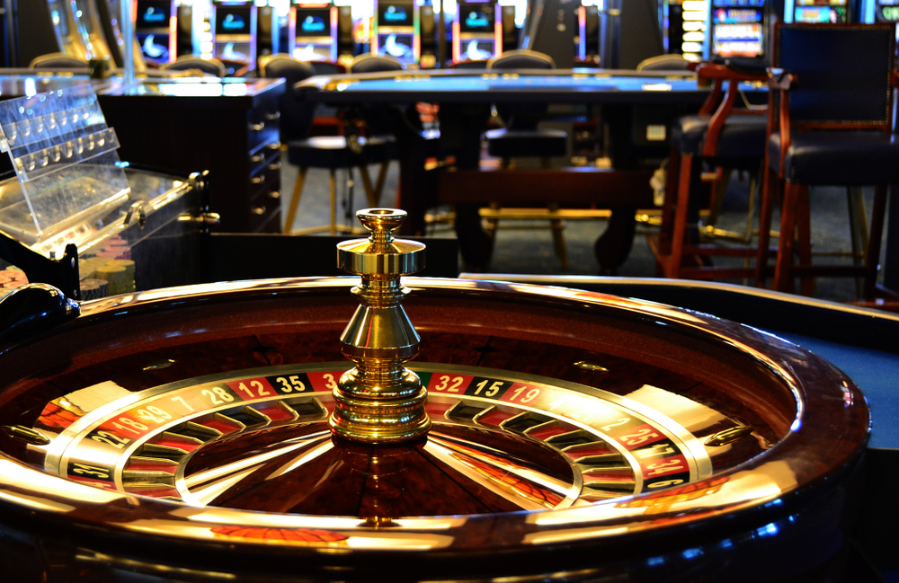 roulette wheel and table at casino facility with slot machines in the background