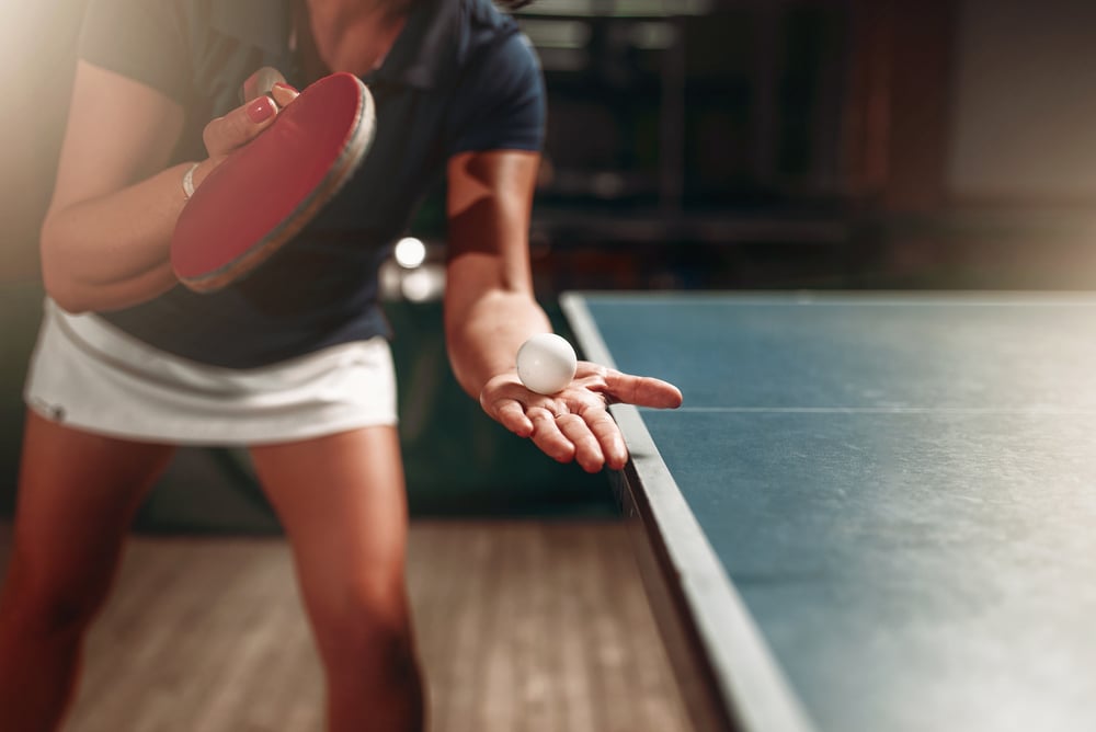 female table tennis player holding ball and racket