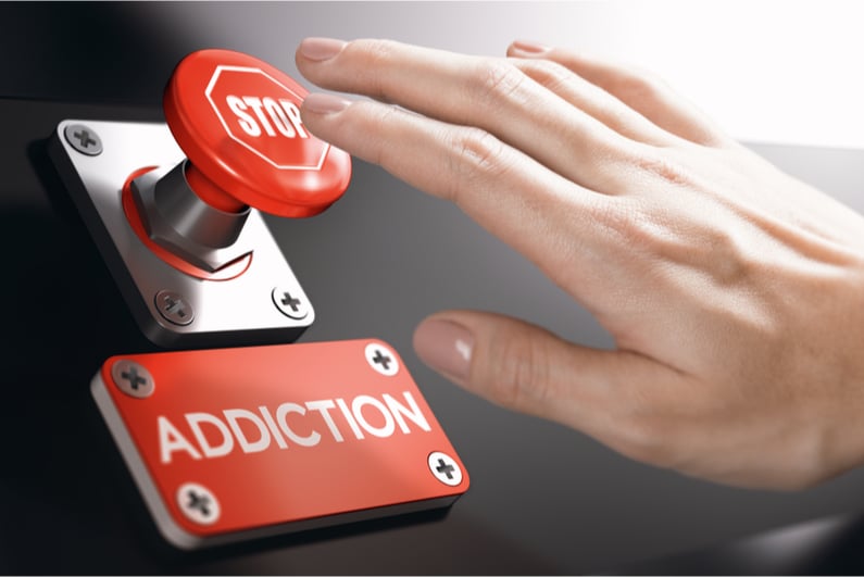 person pressing stop button above addiction sign