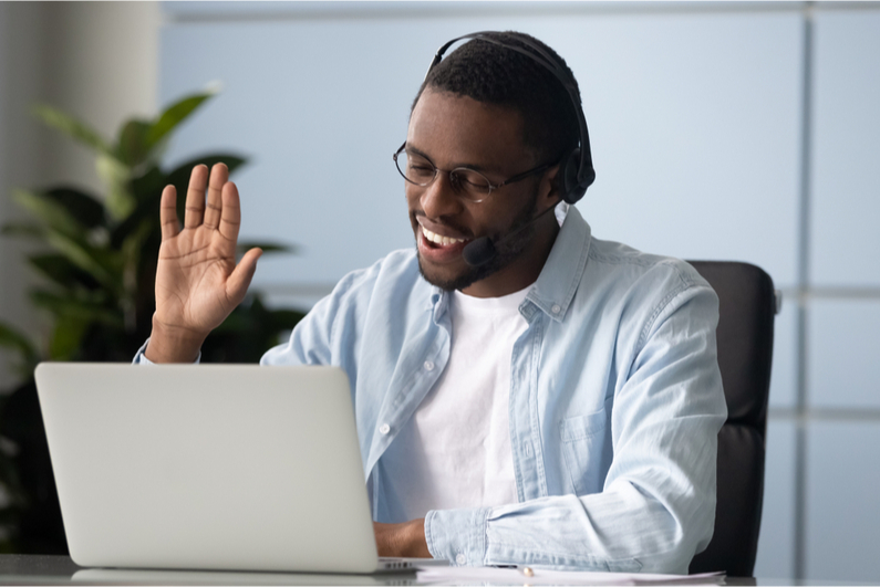 man waving to webcam on his laptop