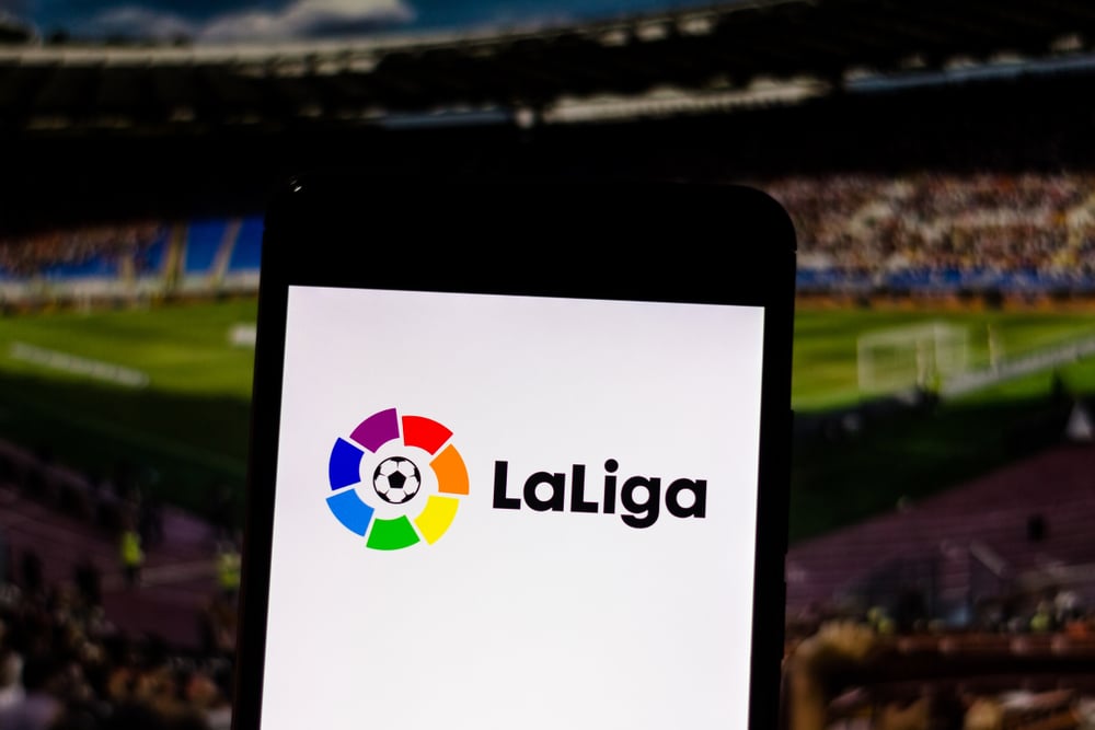 LaLiga logo on smartphone against soccer match background