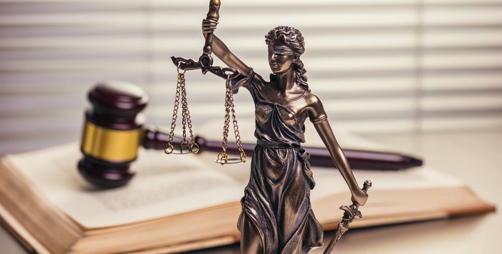 bronze statuette of Lady Justice with judge's gavel on open law book in the background